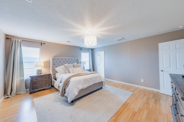 bedroom with multiple windows, a textured ceiling, and light hardwood / wood-style flooring