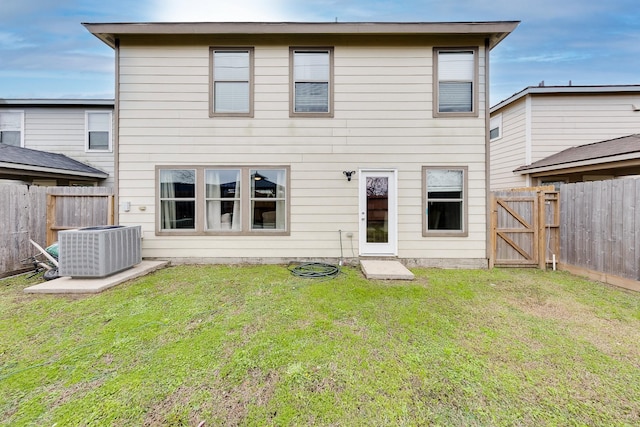 rear view of property featuring cooling unit and a lawn