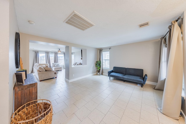 tiled living room with ceiling fan and a textured ceiling