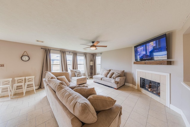 living room featuring ceiling fan, light tile patterned floors, a textured ceiling, and a fireplace