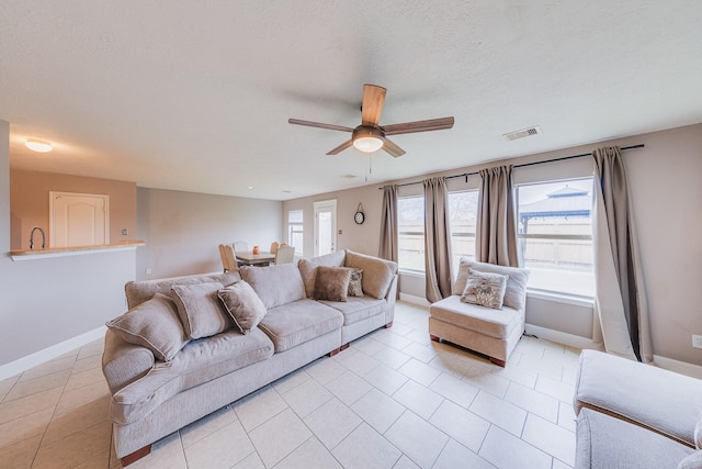 living room featuring light tile patterned flooring, ceiling fan, and a textured ceiling