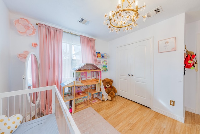 bedroom featuring hardwood / wood-style flooring, an inviting chandelier, and a closet