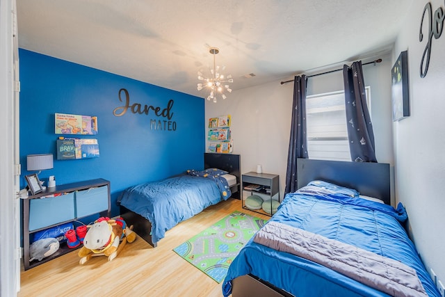 bedroom with hardwood / wood-style floors, a notable chandelier, and a textured ceiling