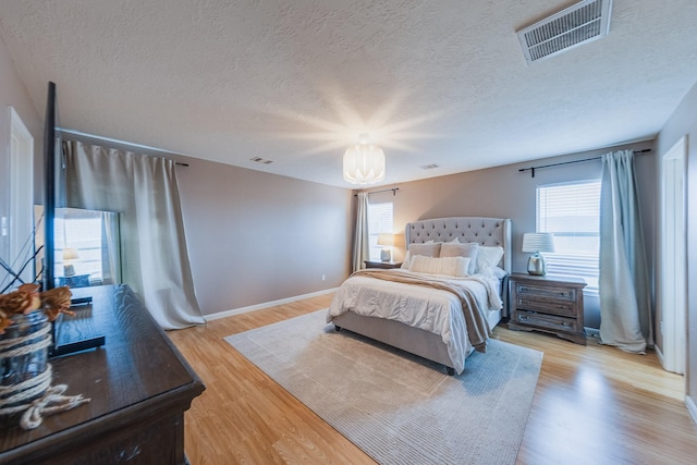 bedroom with light hardwood / wood-style flooring and a textured ceiling