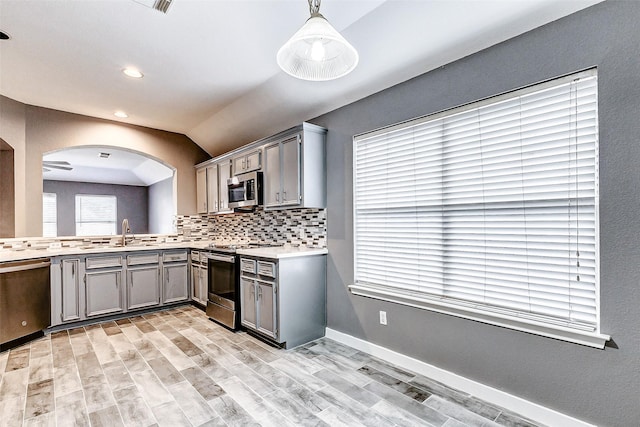 kitchen featuring tasteful backsplash, appliances with stainless steel finishes, decorative light fixtures, and gray cabinets