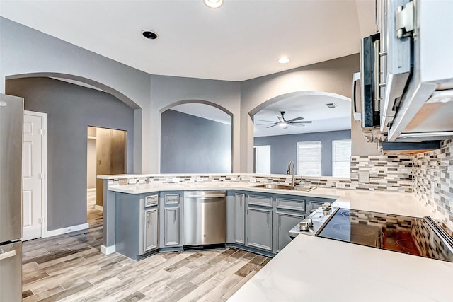 kitchen with sink, light hardwood / wood-style flooring, appliances with stainless steel finishes, gray cabinets, and kitchen peninsula