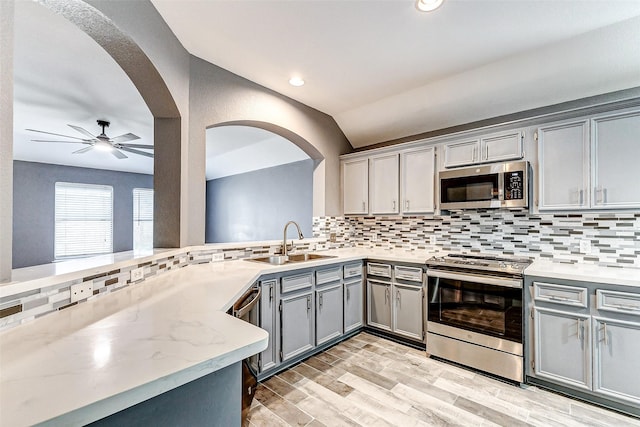 kitchen featuring sink, appliances with stainless steel finishes, gray cabinets, ceiling fan, and decorative backsplash