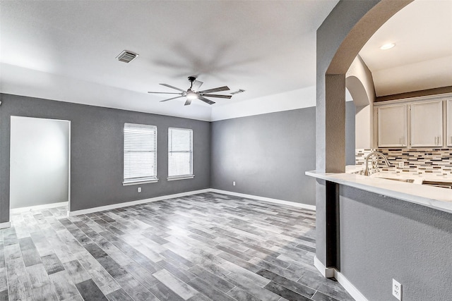 unfurnished living room featuring ceiling fan, sink, and light wood-type flooring