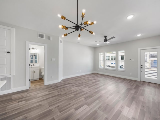 unfurnished living room with ceiling fan with notable chandelier, a healthy amount of sunlight, sink, and light hardwood / wood-style floors