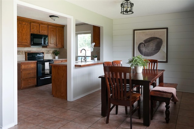 tiled dining area featuring sink and wooden walls