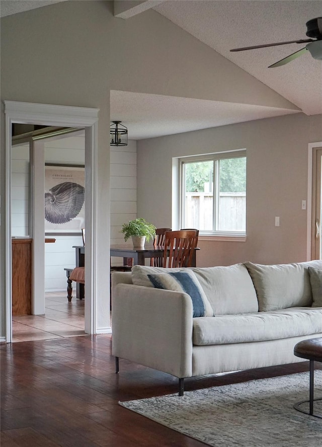 living room featuring ceiling fan, vaulted ceiling, dark hardwood / wood-style flooring, and a textured ceiling