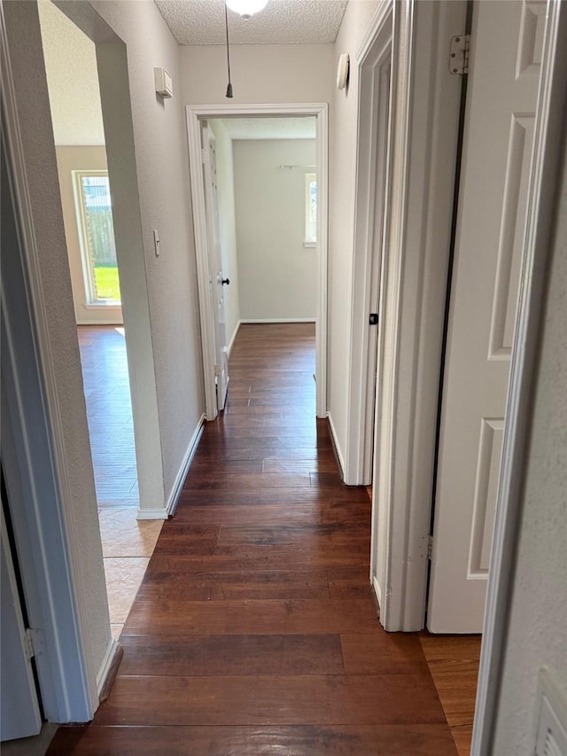 corridor featuring a textured ceiling and dark wood-type flooring