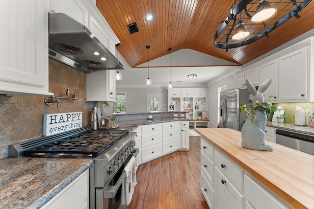 kitchen with butcher block countertops, white cabinetry, stainless steel appliances, decorative light fixtures, and exhaust hood