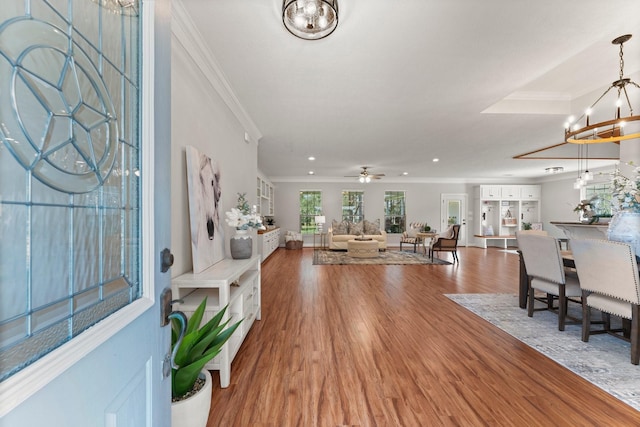 entrance foyer featuring hardwood / wood-style floors, crown molding, and ceiling fan with notable chandelier