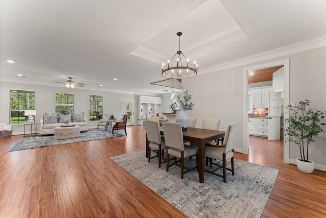 dining space featuring a tray ceiling, hardwood / wood-style flooring, and crown molding