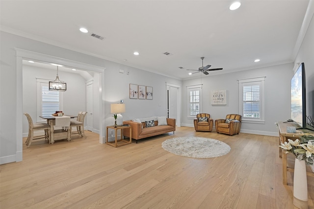 living room featuring ornamental molding, ceiling fan with notable chandelier, and light hardwood / wood-style flooring