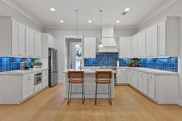 11 Caravelle Ct, Galveston, TX 77554 - kitchen featuring appliances with stainless steel finishes, premium range hood, decorative backsplash, a kitchen island with sink, and white cabinetry