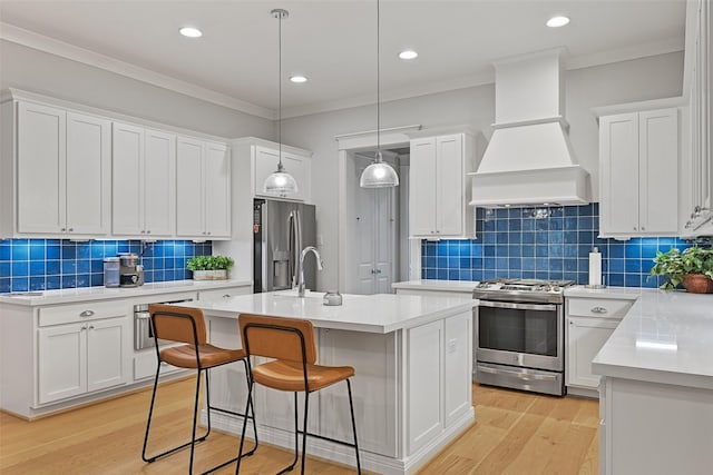 kitchen featuring pendant lighting, white cabinets, custom exhaust hood, stainless steel appliances, and a center island with sink