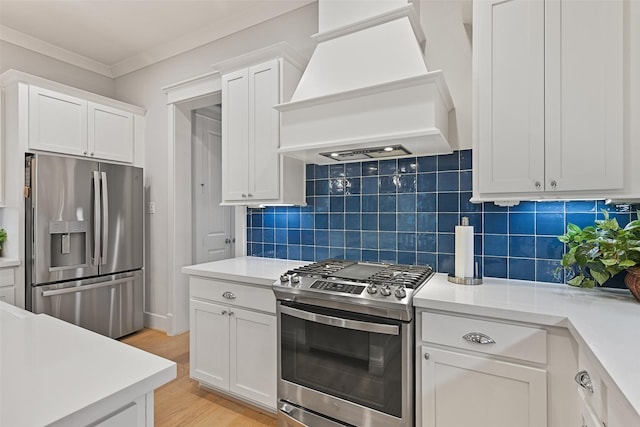 11 Caravelle Ct, Galveston, TX 77554 - kitchen featuring stainless steel appliances, custom range hood, white cabinetry, light countertops, and ornamental molding
