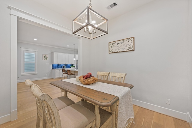 dining space featuring crown molding, light hardwood / wood-style flooring, and a chandelier