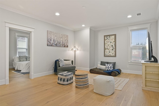 living area featuring ornamental molding and light hardwood / wood-style flooring