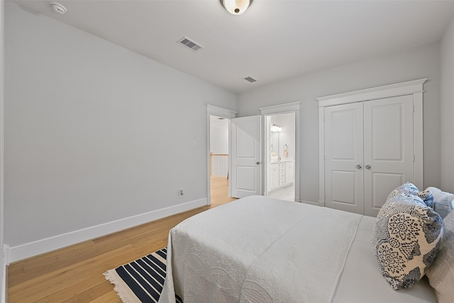 bedroom with wood-type flooring, connected bathroom, and a closet