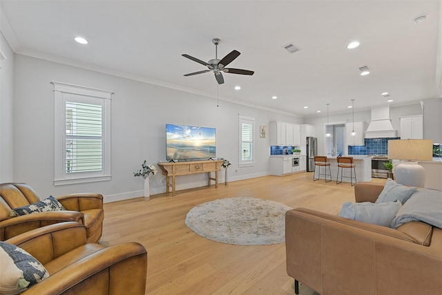 living room with ornamental molding, ceiling fan, and light wood-type flooring