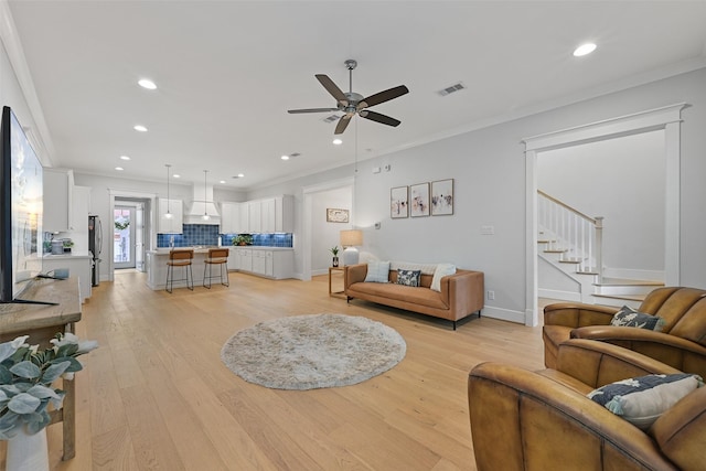 living room with crown molding, ceiling fan, and light wood-type flooring