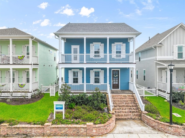 view of front of home with a balcony, covered porch, and a front yard