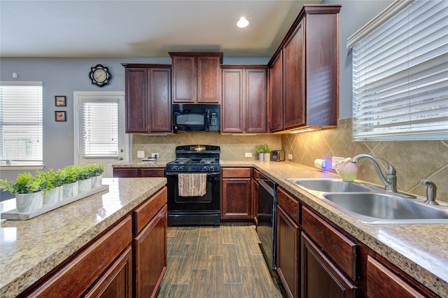 kitchen featuring tasteful backsplash, wood finished floors, light countertops, black appliances, and a sink