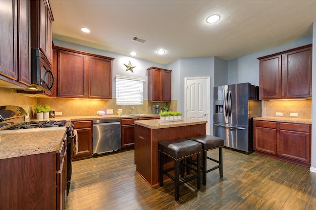 kitchen featuring visible vents, dark wood-style floors, a breakfast bar area, a center island, and stainless steel appliances