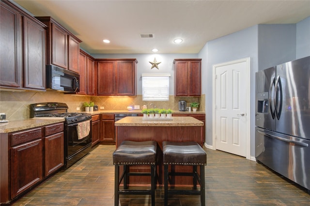 kitchen featuring a center island, dark wood-style flooring, light countertops, and black appliances