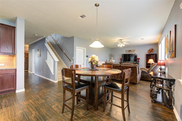 dining area with dark wood-style flooring, a ceiling fan, visible vents, baseboards, and stairway