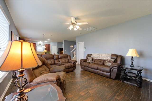 living area featuring baseboards, visible vents, a ceiling fan, dark wood-style floors, and stairway