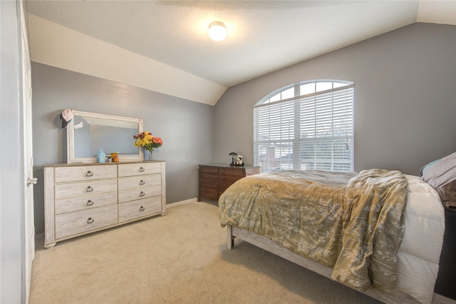 bedroom with lofted ceiling, light colored carpet, and baseboards