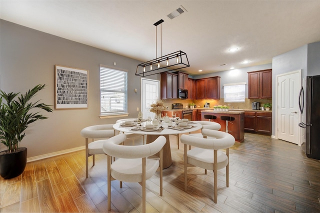 dining room featuring baseboards, visible vents, wood finished floors, and recessed lighting