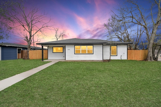 ranch-style house featuring fence and a yard