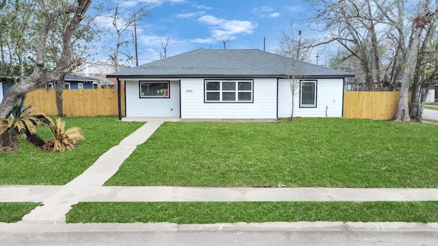 view of front of house featuring a front lawn, fence, and roof with shingles