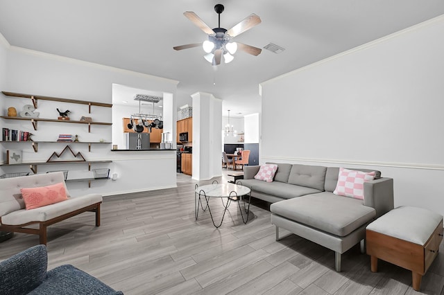 living room with light wood-type flooring, visible vents, crown molding, and ceiling fan with notable chandelier