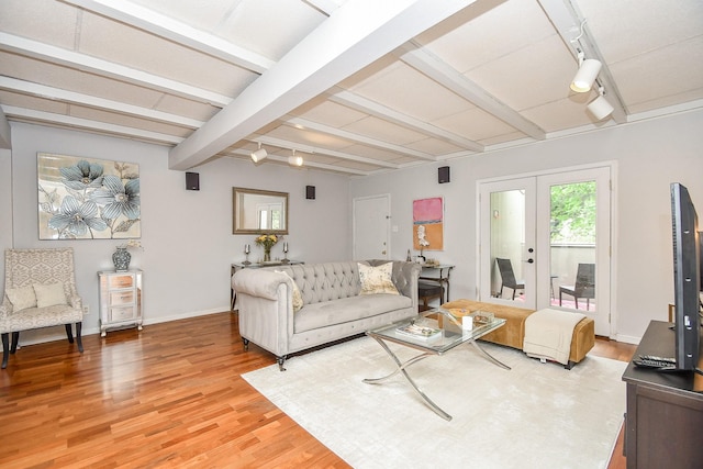 living room with hardwood / wood-style floors, beam ceiling, track lighting, and french doors