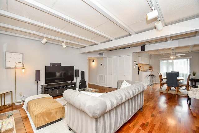 living room featuring beam ceiling, hardwood / wood-style flooring, and track lighting