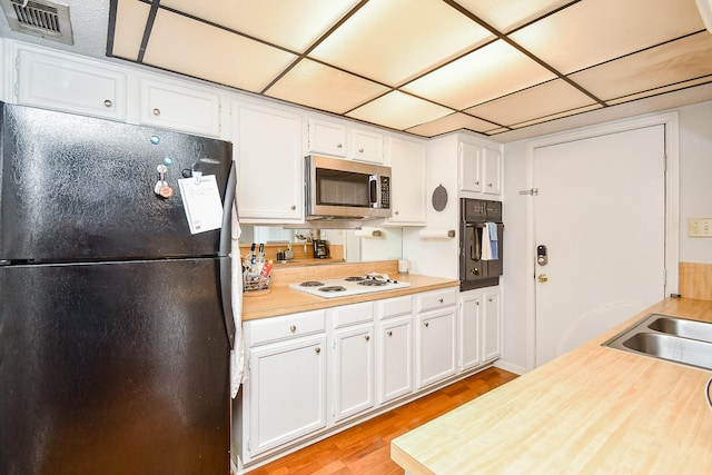 kitchen featuring sink, light hardwood / wood-style flooring, white cabinets, and black appliances