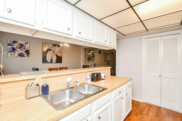 kitchen featuring white cabinetry, sink, and light wood-type flooring