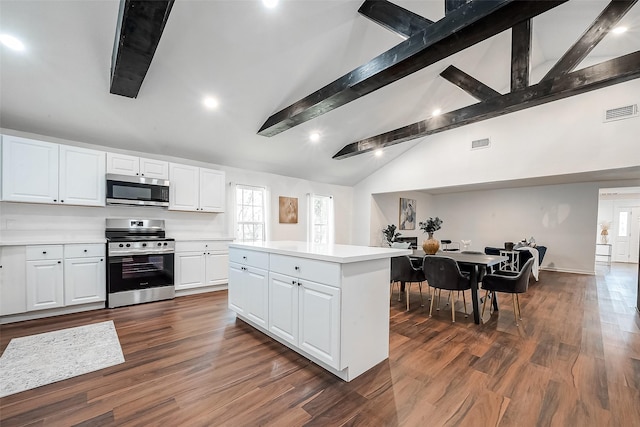 kitchen featuring vaulted ceiling with beams, stainless steel appliances, dark hardwood / wood-style floors, a center island, and white cabinets