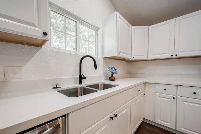 kitchen featuring dishwasher, sink, and white cabinets