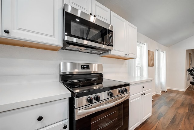 kitchen featuring white cabinetry, dark wood-type flooring, stainless steel appliances, and lofted ceiling