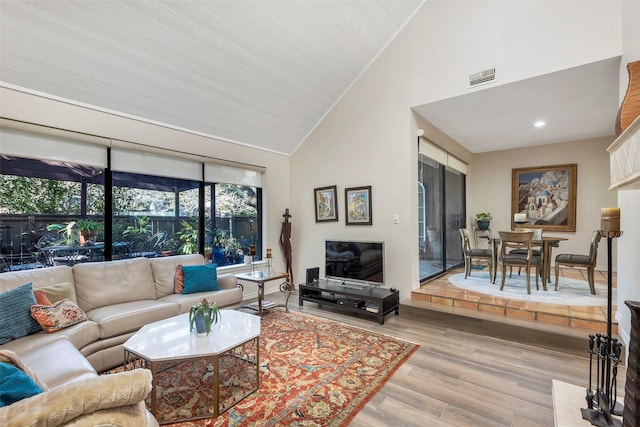 living room with crown molding, high vaulted ceiling, and light wood-type flooring