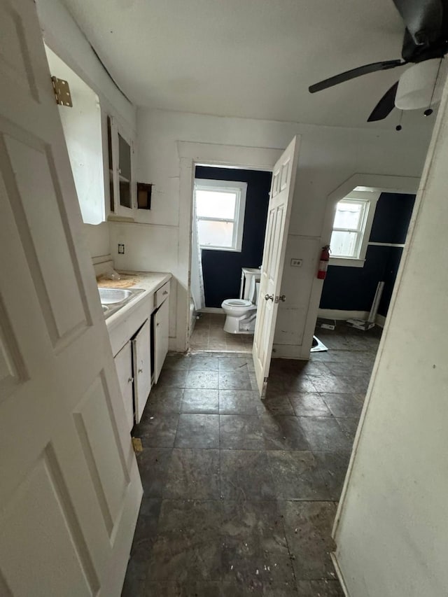 bathroom featuring ceiling fan, vanity, toilet, and a wealth of natural light