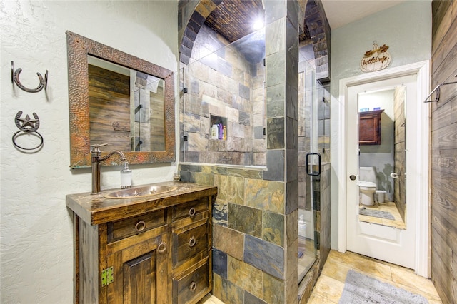 bathroom with toilet, vanity, and a shower with shower door