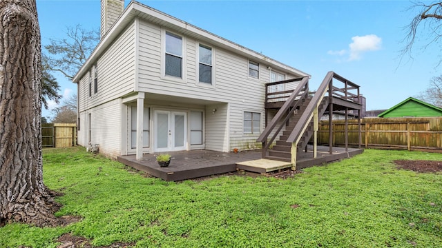 rear view of property featuring a wooden deck, a lawn, and french doors